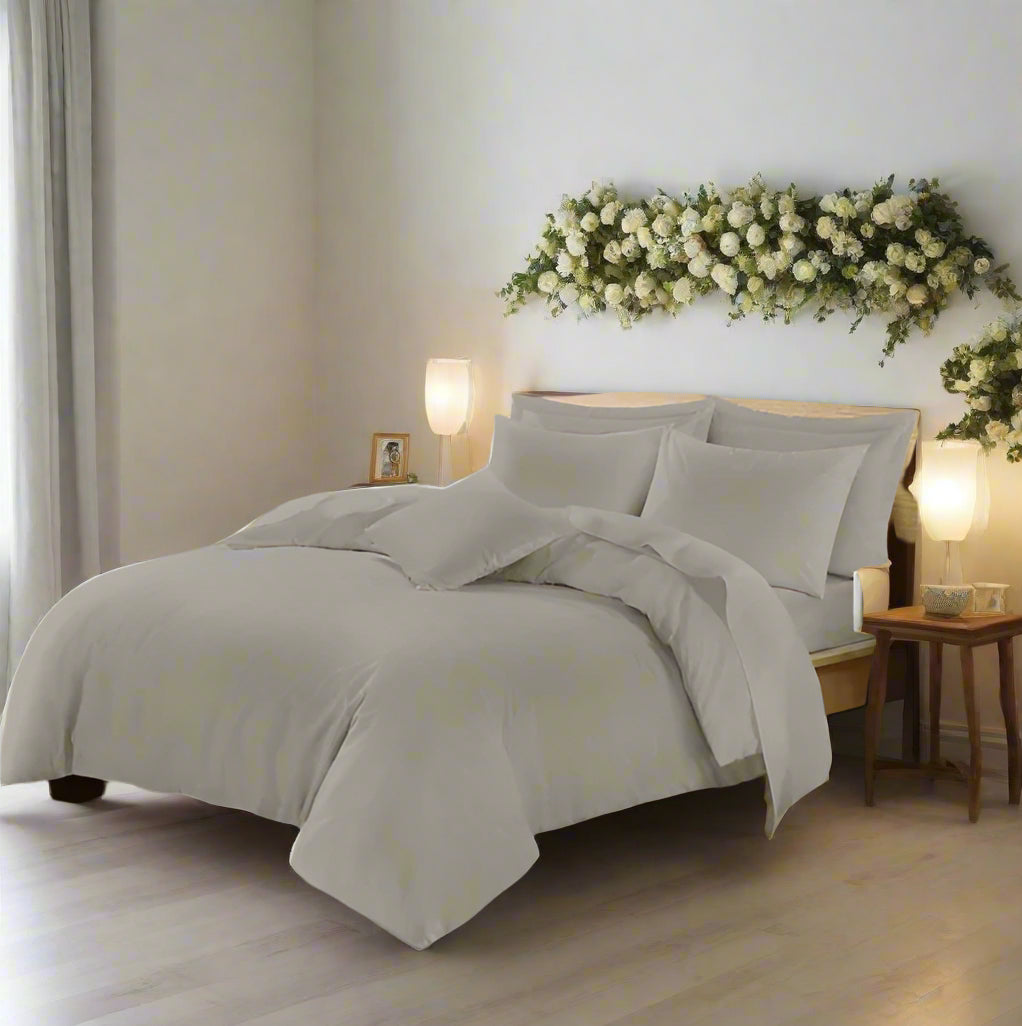 Neatly made bed with light gray bedding in a bedroom setting.