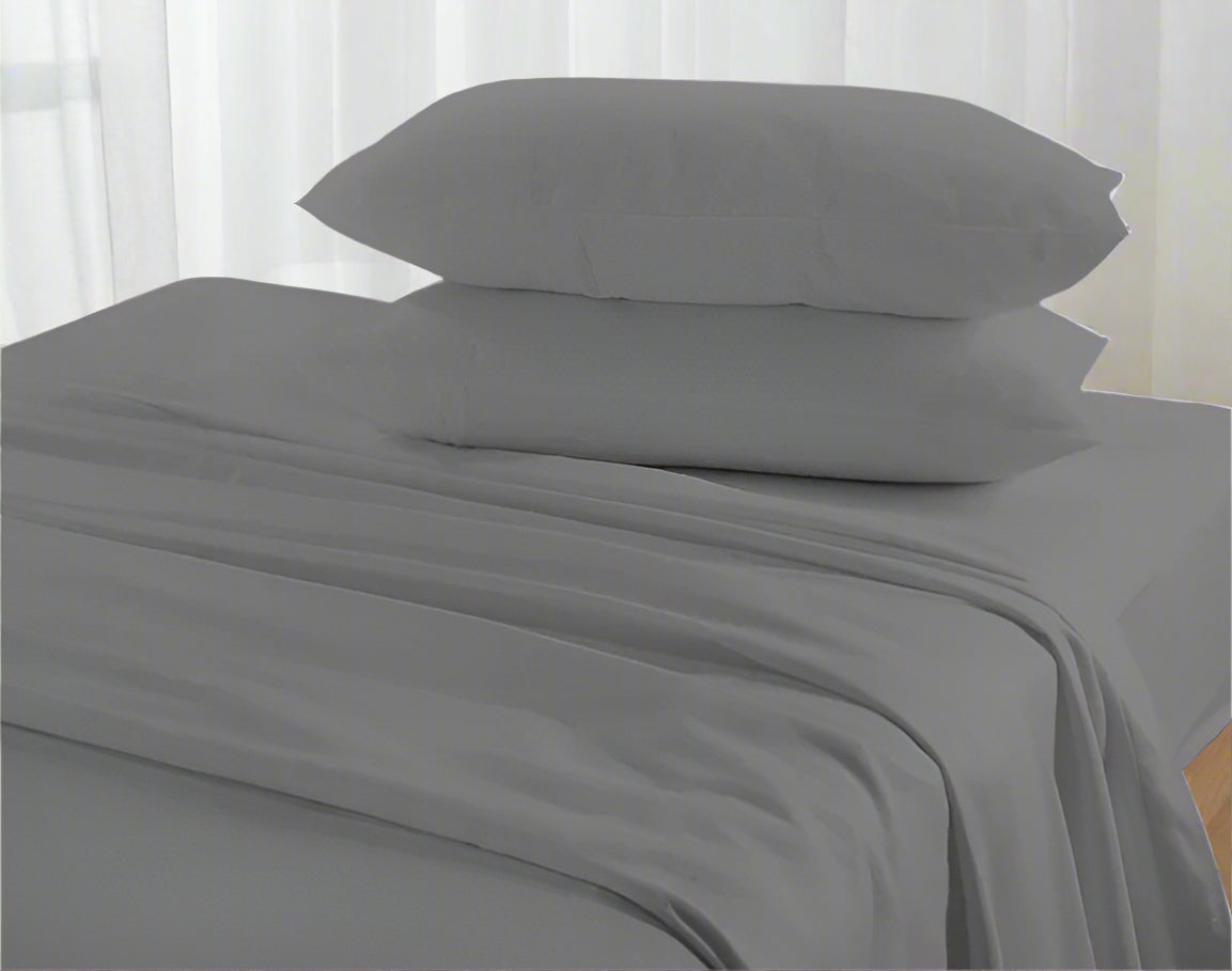 Gray bed sheets and pillows on a bed with a neutral background