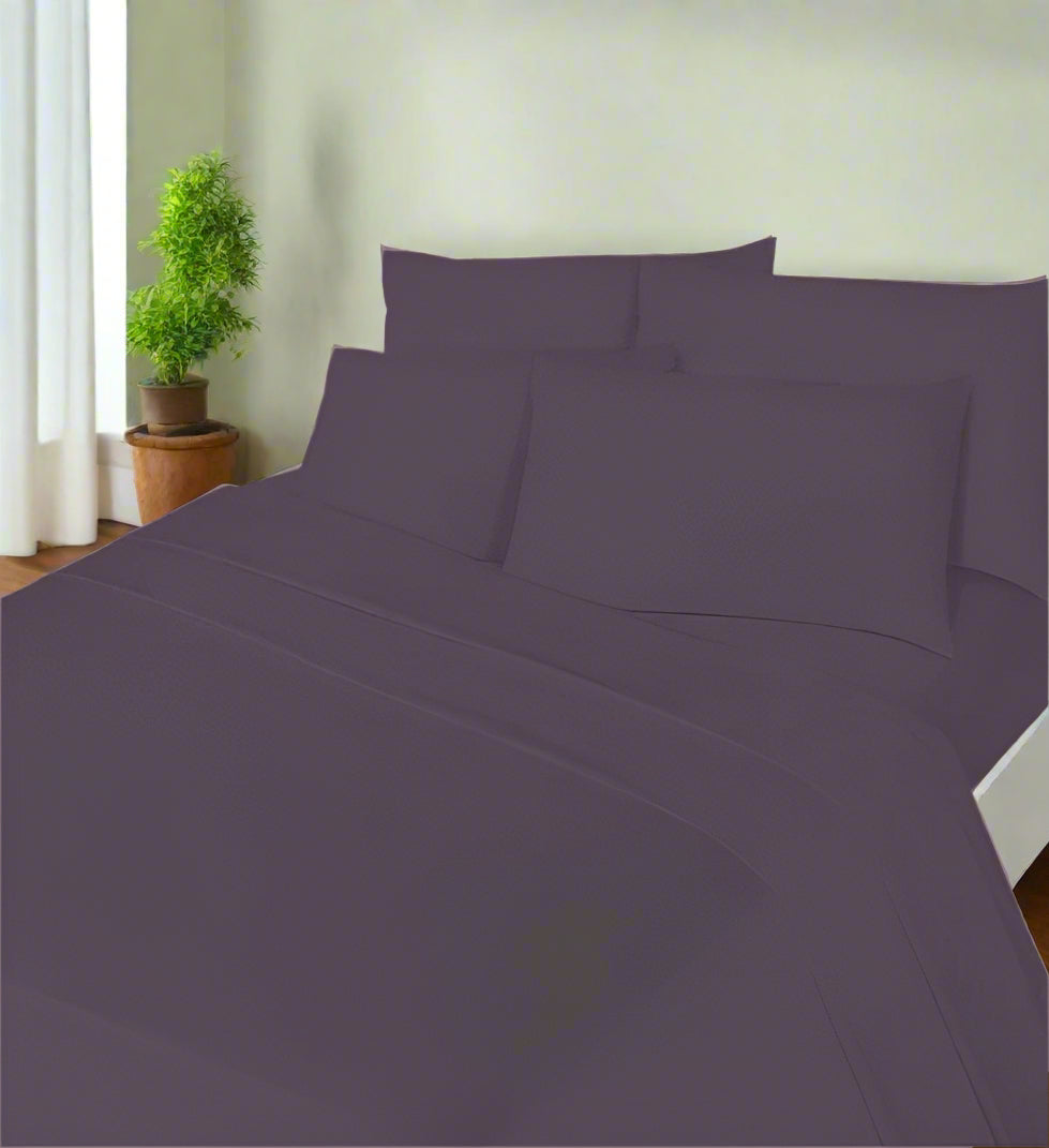 Purple bed sheets and pillows on a bed in a bedroom setting.