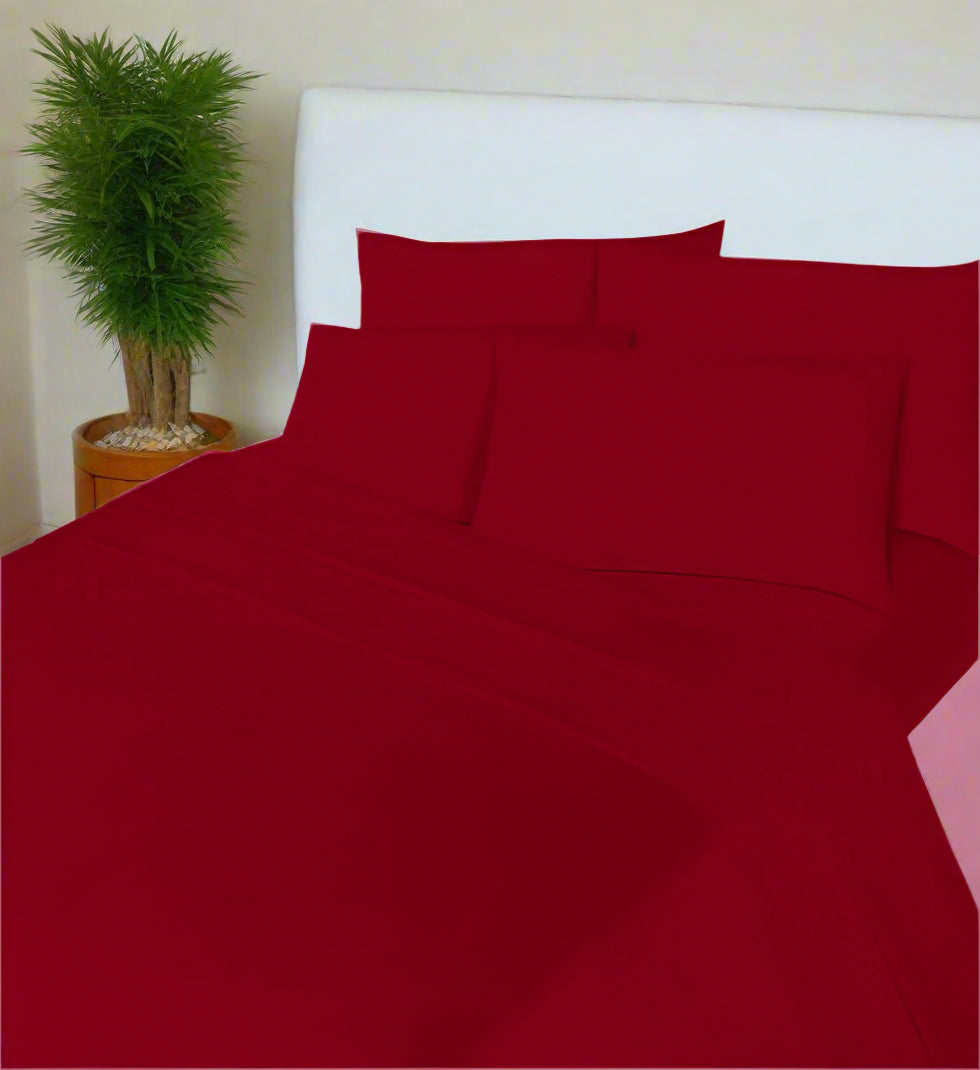 Red bedspread set on a neatly made bed in a bedroom.