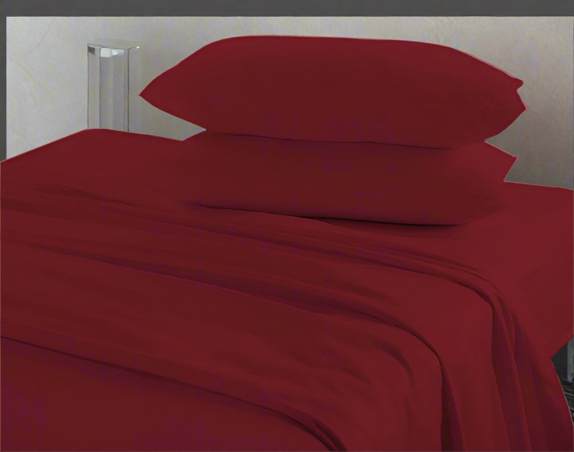 Red bed sheets and pillows on a bed with a neutral background