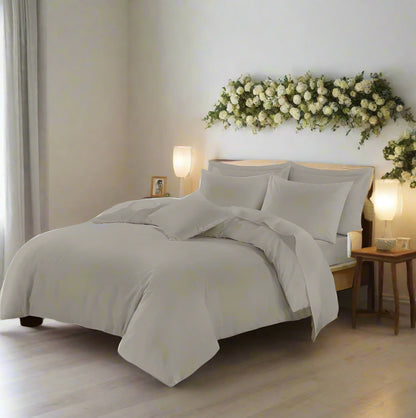 Neatly made bed with light gray bedding in a bedroom setting.