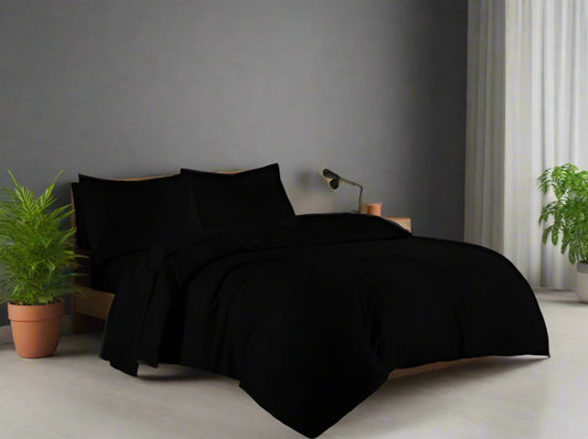 Black bedding set on a bed in a bedroom with a window in the background