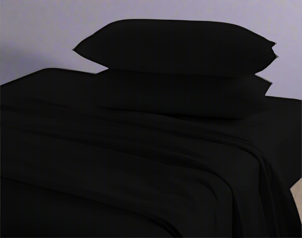 Black bed sheets and pillows on a bed with a neutral background