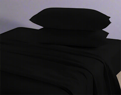 Black bed sheets and pillows on a bed with a neutral background