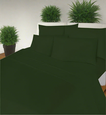 Green bed sheet set on a bed with pillows in a room with a window.