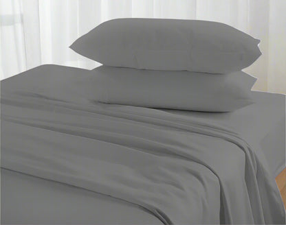 Gray bed sheets and pillows on a bed with a neutral background